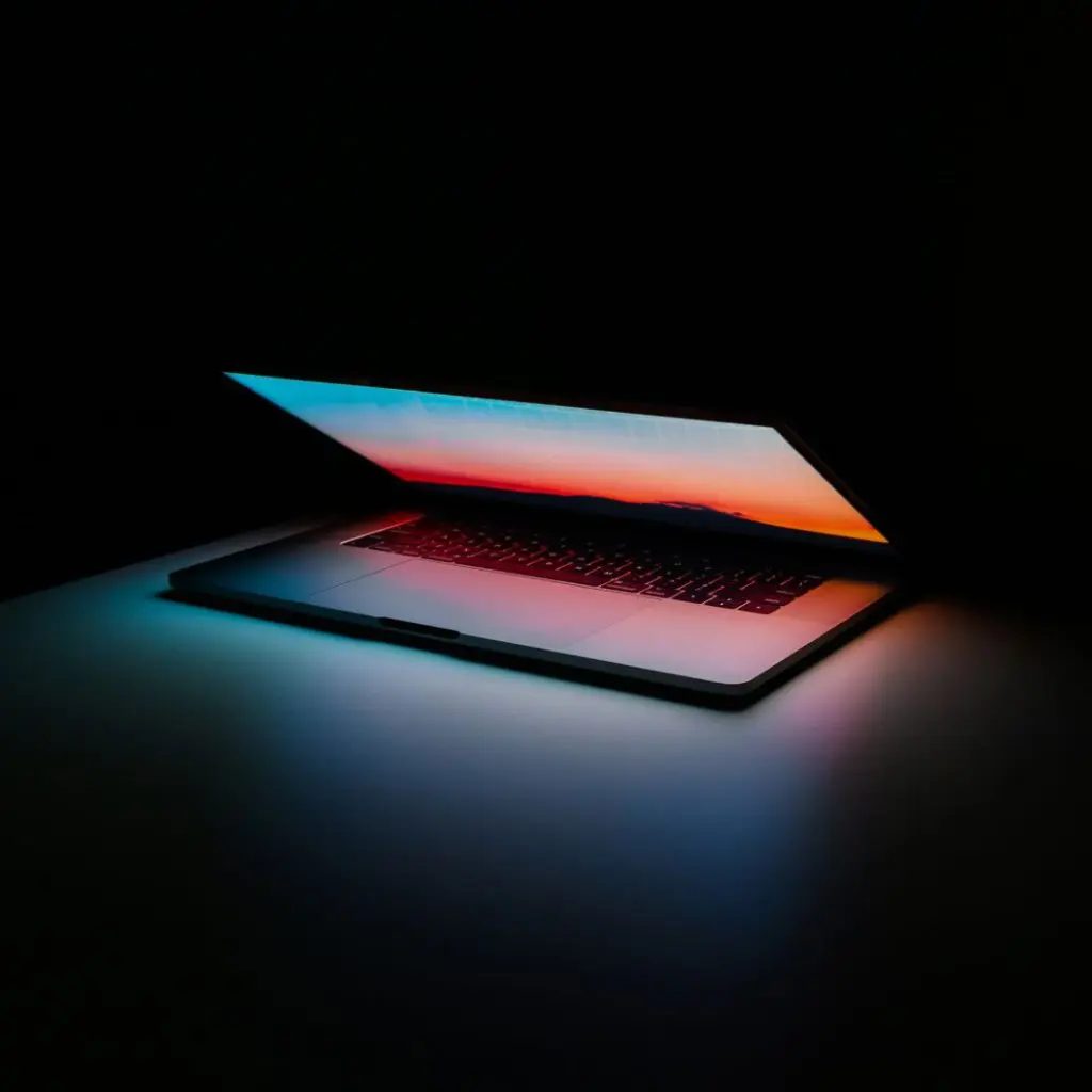 Open Laptop in the dark showing a color spectrum similar to a sunset.